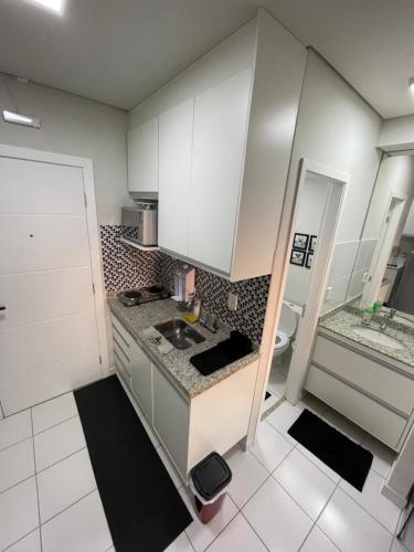 a small kitchen with white cabinets and a sink at Studio completo e aconchegante in Ribeirão Preto