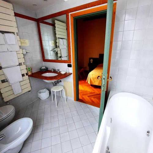 a bathroom with a toilet and a sink and a bed at Hotel Bellavista in Abetone