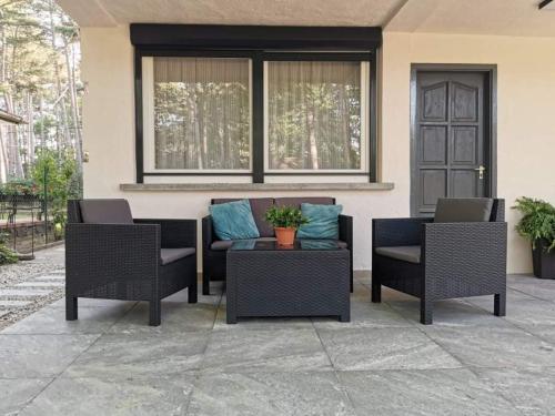 eine Terrasse mit drei Stühlen, einem Tisch und einem Fenster in der Unterkunft Mobius Haus in Siófok