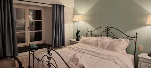 a bedroom with a bed with white sheets and a window at Le Maissin 1876 in Paliseul