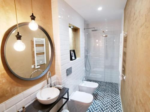 een badkamer met 2 toiletten, een wastafel en een spiegel bij Apartamentos Tres Llaves Palacio de Vela de los Cobos in Úbeda