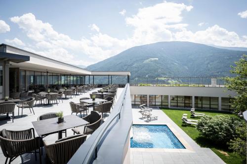 a balcony with tables and chairs and a swimming pool at Das Mühlwald - Quality Time Family Resort in Natz-Schabs