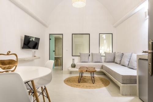 a white living room with a couch and a table at Anila Suites in Fira