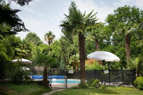 une piscine avec des palmiers et une clôture dans l'établissement Maison CHILO, à Barcus
