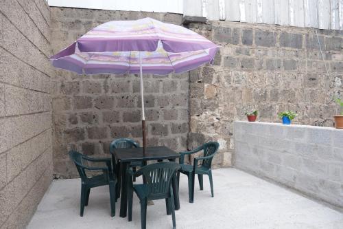 una mesa negra con sombrilla y sillas moradas en Guest House Kumayri, en Gyumri