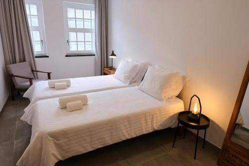 1 dormitorio con 2 camas con sábanas blancas y lámpara en Casas do Mercado - Casa Sirius en Angra do Heroísmo