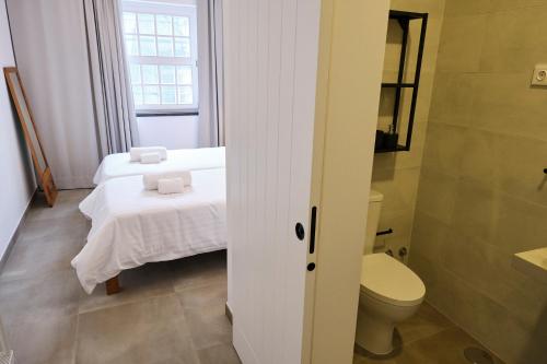Un pequeño baño con dos camas y un inodoro. en Casas do Mercado - Casa Sirius, en Angra do Heroísmo
