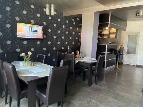 una sala da pranzo con tavoli, sedie e TV a parete di Pensiunea exotic a Craiova