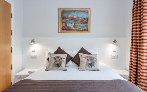 a bedroom with a bed with pillows and a painting at High Range Lodge Hotel in Aviemore