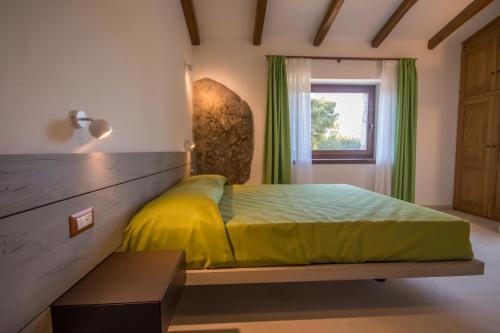 a bedroom with a yellow bed and a window at Villa Ginepro (Country House) in Dorgali
