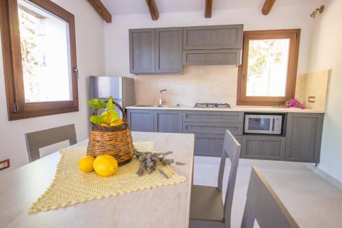una cocina con una mesa con una cesta de fruta. en Villa Ginepro (Country House), en Dorgali