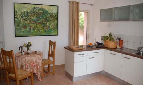 - une cuisine avec des placards blancs, une table, une table et des chaises dans l'établissement Villa Melocoton, à Figanières
