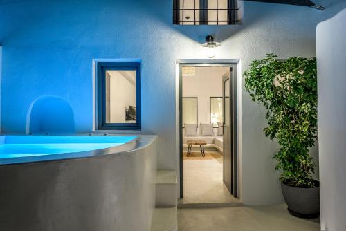a bathroom with a blue tub and a potted plant at Anila Suites in Fira