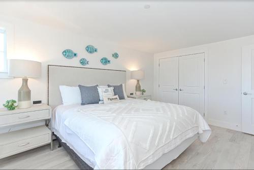 a white bedroom with a large white bed and white cabinets at Harbortown Suites in Plymouth