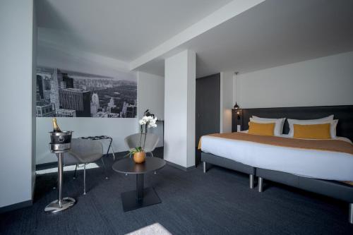 ラ・ロシェルにあるCentral Park Hôtel & Spaのベッドとテーブルが備わるホテルルームです。