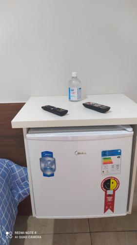 a white counter with two remote controls on top of a refrigerator at Pousada Quarto família ar, frigobar,wi fi in Aparecida