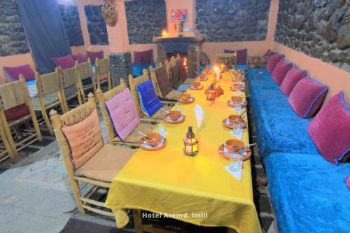 a long table with a yellow table cloth and chairs at Hotel Igoudar Armed in Imlil