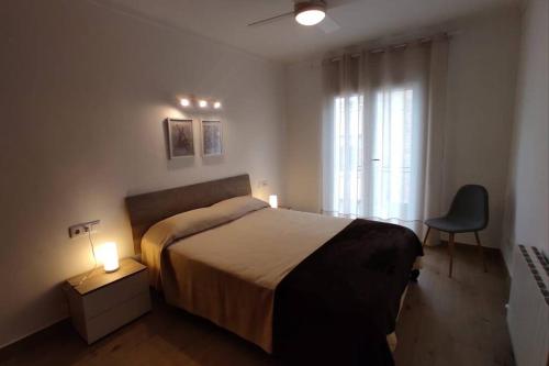 um quarto com uma cama, uma cadeira e uma janela em Can Puig. amplio, luminoso y con gran terraza. em Palafrugell