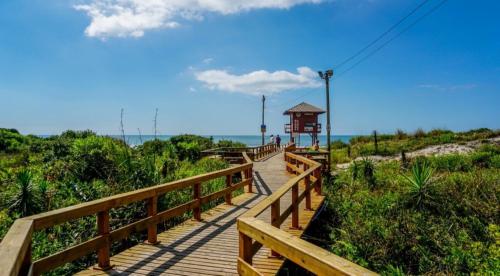 a wooden boardwalk leading to a gazebo on the beach at Villa Giardino - Condomínio de Frente para o Mar - Piscina, Quadra Esportiva, Churrasqueira - 5 Pessoas in Florianópolis