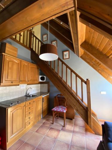 a kitchen with wooden cabinets and a staircase at Aparthotel Es de Don Joan in Unha