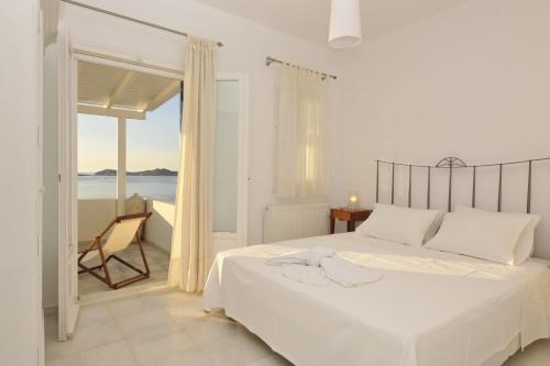 um quarto branco com uma cama e vista para o oceano em Armenistis Apartment em Naousa