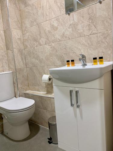 a bathroom with a white sink and a toilet at De Regency Style Hotel in Redditch