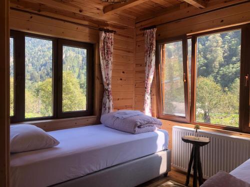 a bedroom with two beds in a wooden cabin with windows at Çamdibi Konaklama in Rize