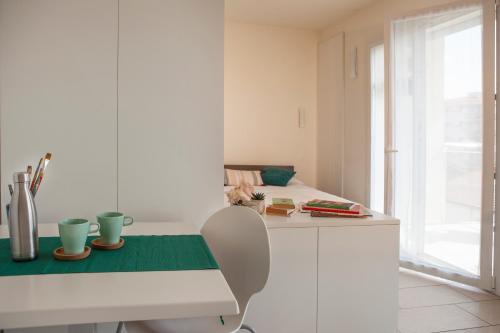 a white kitchen with a table with a green runner at Residence Sunrise in Cesenatico