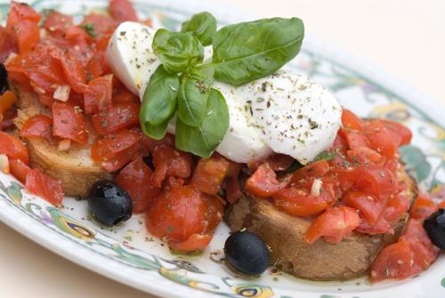 a plate of food with tomatoes and poached eggs at Hotel Terme Villa Teresa in Ischia