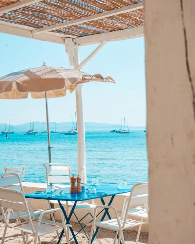 a table with chairs and an umbrella on the beach at Hôtel Lido Beach in Hyères