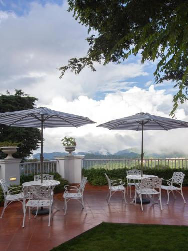 a patio with tables and chairs and umbrellas at Daleside Manor, Boutique Hotel, Kasauli in Kasauli