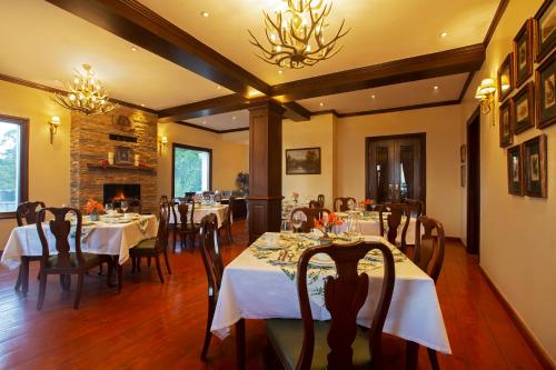 a dining room with tables and chairs and a fireplace at Daleside Manor, Boutique Hotel, Kasauli in Kasauli