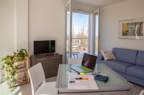 a living room with a blue couch and a table with a laptop at Residence Sunrise in Cesenatico