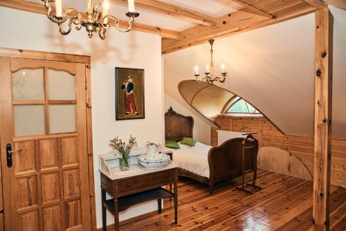 a bedroom with a bed and a table and a door at Impresja - pokoje gościnne na nadbużańskich łąkach in Borsuki