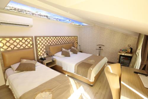 a bedroom with two beds and a table and a window at Unluselek Hotel in Anamur