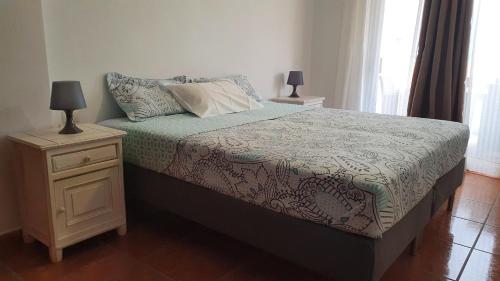 um quarto com uma cama e uma mesa de cabeceira com 2 candeeiros em Aguamarina 433 em San Miguel de Abona