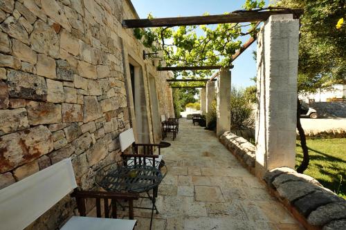 a stone walkway with chairs and a stone wall at Masseria Trulli e Vigne in Martina Franca