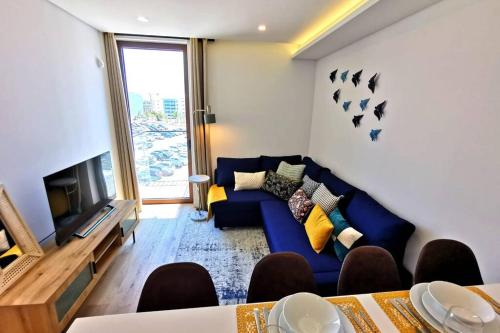 a living room with a blue couch and a tv at 188 Avenue, Aveiro Centro in Aveiro