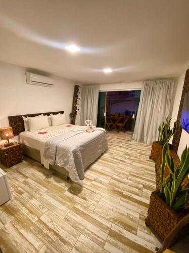 a bedroom with a bed and a wooden floor at CHOUPANA SUÍTES in Japaratinga