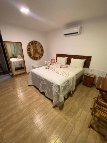 a bedroom with a large bed with a clock on the wall at CHOUPANA SUÍTES in Japaratinga