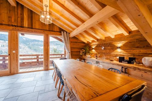 a large wooden table in a room with a large window at Chalet ''la cabane ô Pierres'' 12 pers spa et sauna in Ventron