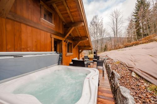a hot tub on a deck next to a house at Chalet ''la cabane ô Pierres'' 12 pers spa et sauna in Ventron