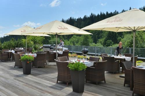 a restaurant with tables and umbrellas on a deck at Omnia Hotel Relax & Wellness in Janske Lazne