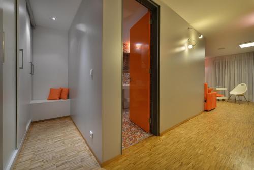 a hallway with an orange door and a bathroom at Omnia Hotel Relax & Wellness in Janske Lazne