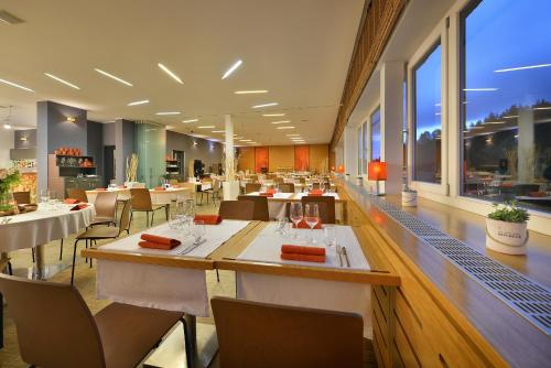 a restaurant with white tables and chairs and windows at Omnia Hotel Relax & Wellness in Janske Lazne
