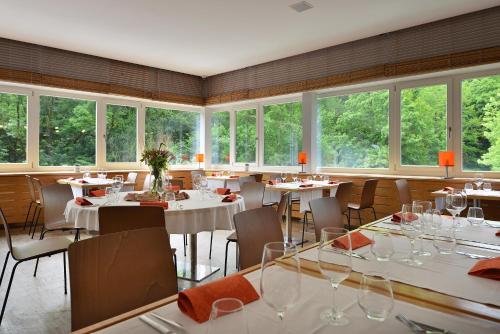 a restaurant with white tables and chairs and windows at Omnia Hotel Relax & Wellness in Janske Lazne