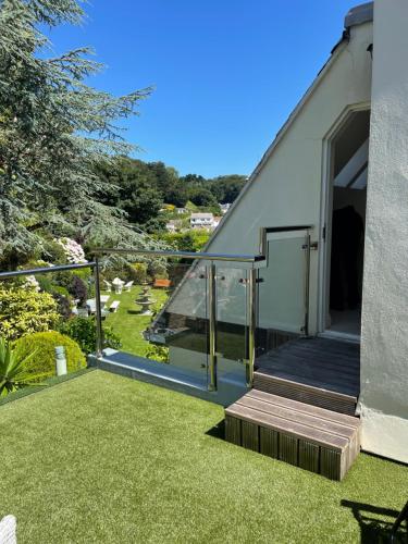 a house with a balcony with a stairway and grass at Porthole Suites in Saint Aubin