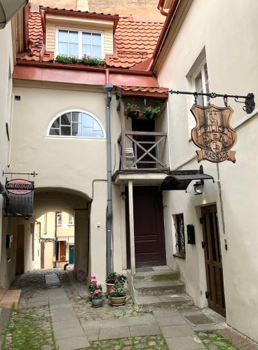 an alley with a building with a balcony and flowers at Very Vilnius Pilies street in Vilnius