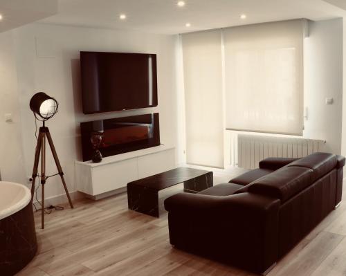 a living room with a couch and a flat screen tv at Black and White Suitte "Plaza" in Noja