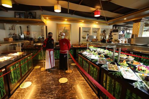 two people standing in a kitchen with food on display at Unluselek Hotel in Anamur